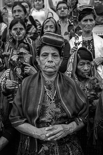 The Trials of the Achi Women by Victor J. Blue _ Credit: © Victor J. Blue, for The New York Times Magazine. Title: The Trials of the Achi WomenCredit: © Victor J. Blue, for The New York Times MagazineCaption: ​​Doña Paulina Ixpatá Alvarado stands with other Achi women outside a Guatemala City court. That afternoon, three ex-civil defense patrollers were found guilty of rape and crimes against humanity and sentenced to 40 years in prison each. Guatemala City, Guatemala, 30 May 2025.Story: For four decades, a group of Indigenous Maya Achi women in Rabinal lived in the same communities as the men who had raped them, sometimes as neighbors. Guatemala’s civil war led to the genocide of thousands of Maya Achi people by the military and local state-backed paramilitary forces, who used sexual violence as a systematic weapon to subjugate Indigenous communities. In 2011, 36 women broke their silence, launching and winning a 14-year legal battle against their abusers. Their collective resilience is transforming a legacy of wartime impunity into a historic victory for justice.